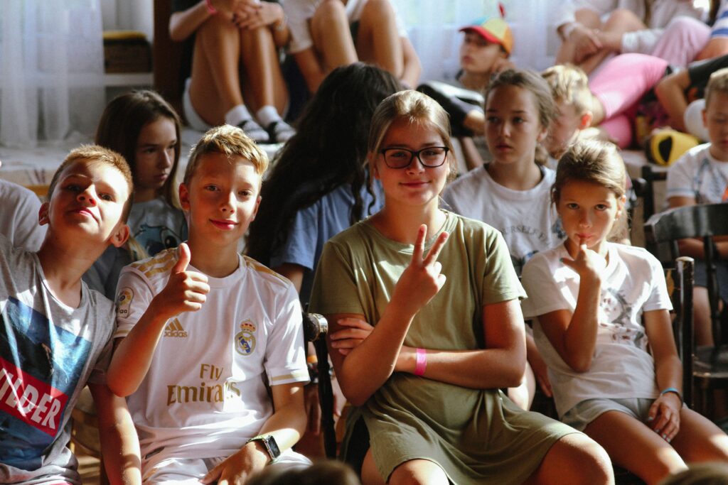 Cheerful group of children sitting together at an indoor event, showcasing friendships and diversity.